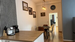 A modern kitchen with a wooden countertop, a coffee machine, and a dining area with a table and chairs. - Cozy Koblenz Apartment With City Views (Koblenz)