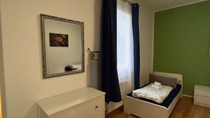 A bedroom with a bed, a dresser, a mirror, and a window with curtains. - Cozy Koblenz Apartment With City Views (Koblenz)