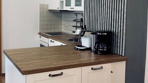 A compact kitchen with white cabinets, a wooden countertop, and a coffee maker. - Cozy Koblenz Apartment With City Views (Koblenz)