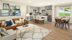 Une cuisine moderne avec des meubles gris, un îlot central et un coin repas comprenant une table et des chaises.