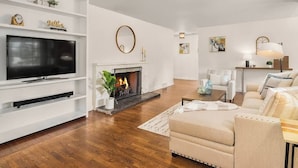 Una sala de estar moderna con televisor, chimenea, sofá y mesa de centro.