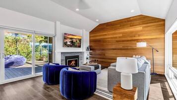 A modern living room with a fireplace, a sofa, and a blue ottoman.