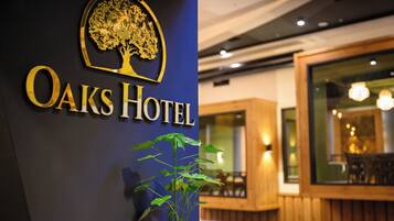 Et hotelskilt med et trælogo og navnet "Oaks Hotel".