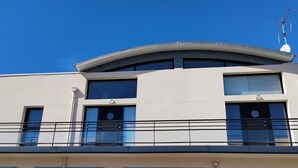 Un bâtiment moderne doté d’un toit incurvé, de grandes fenêtres et d’un balcon agrémenté de balustrades.