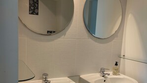 Une salle de bain avec deux lavabos, un miroir et une étagère en verre.