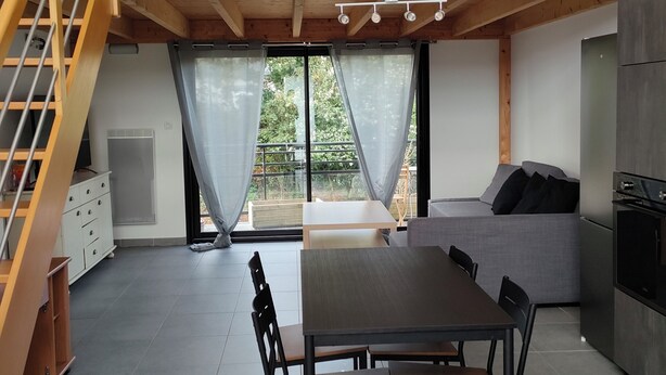 Un intérieur moderne comprenant un coin repas, un canapé, un escalier et une cuisine.