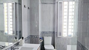 Een moderne badkamer met een groot wastafel, toilet en douche.