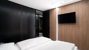 Ein modernes Hotelzimmer mit einem großen Bett, einem Kleiderschrank und einem an der Wand befestigten Flachbildfernseher.