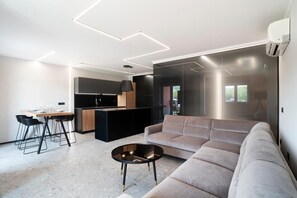 Ein modernes Wohnzimmer mit einer Couch, einem Esstisch mit Stühlen und einer Küchenzeile.