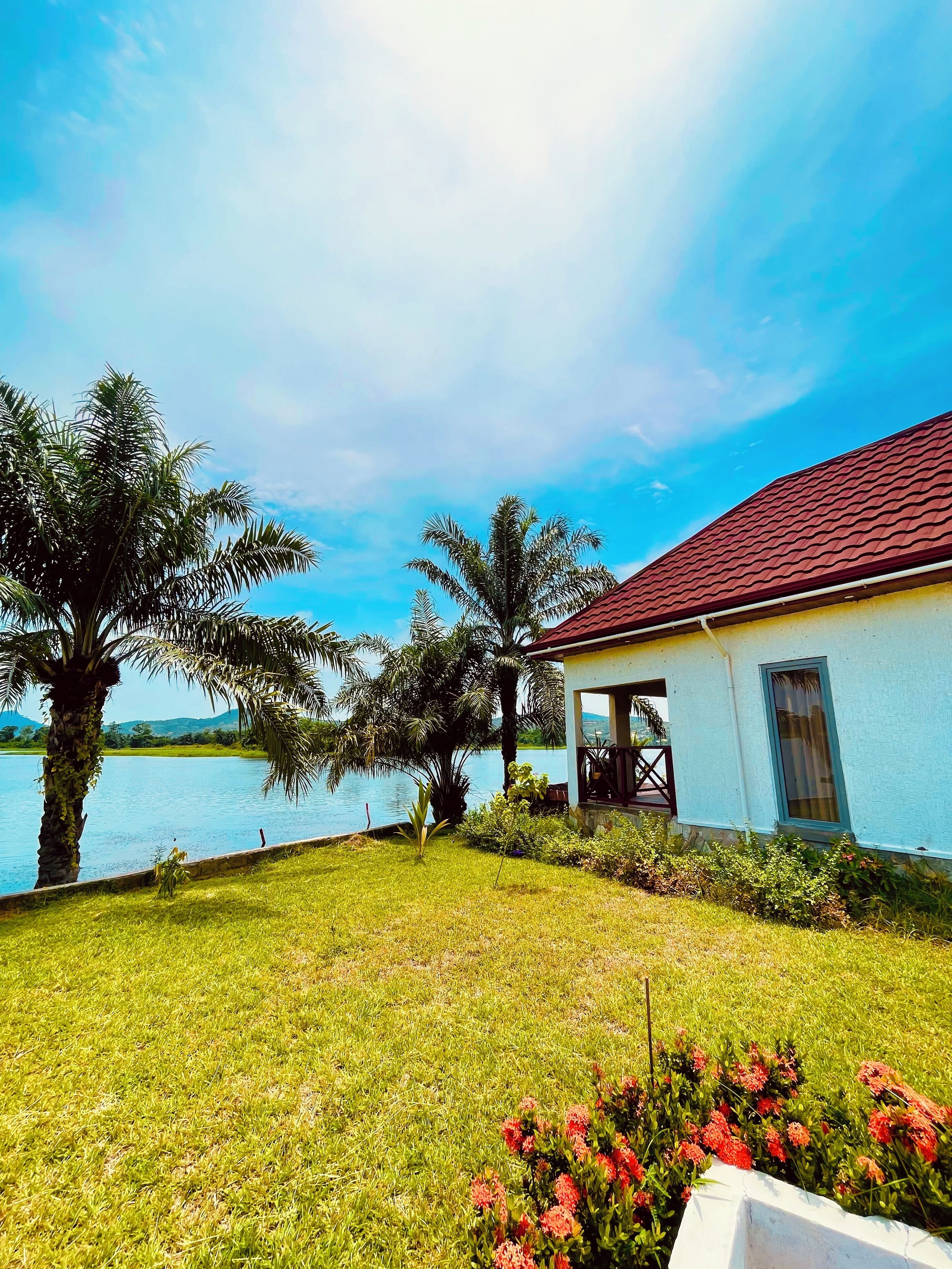 A house with a red roof, a porch, and a view of a lake.