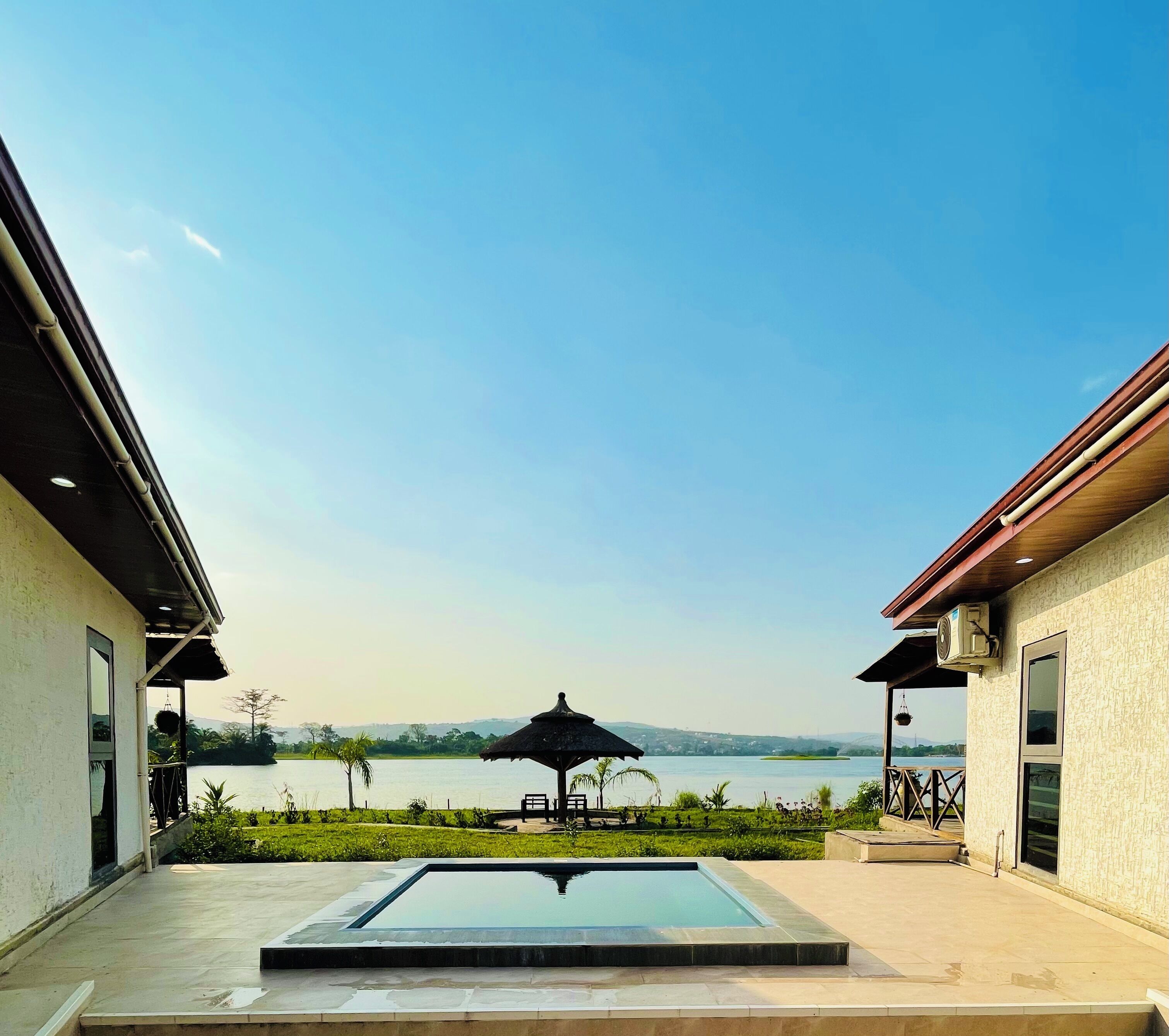 Uma área de piscina com vista para um lago e montanhas, um gazebo e uma área de estar coberta.