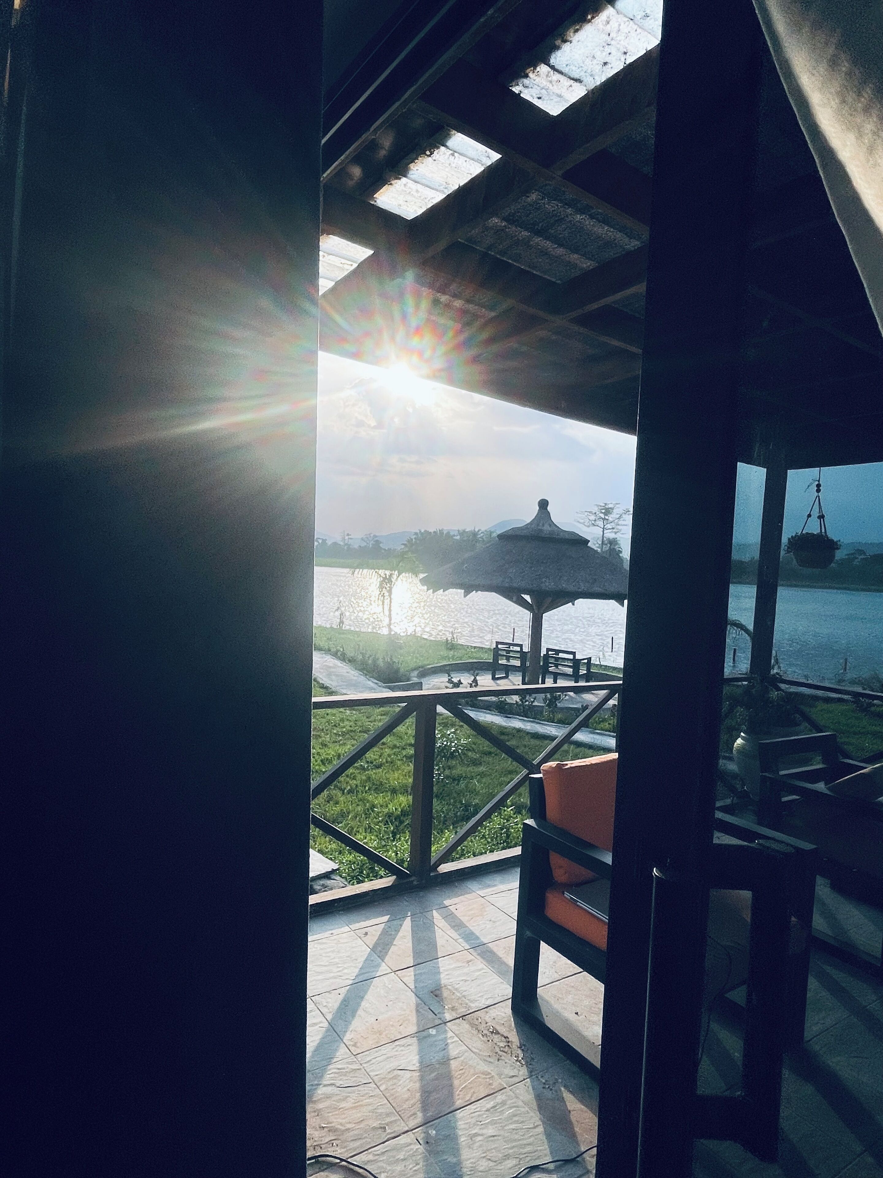 A covered outdoor area with a view of a water body and a distant structure.