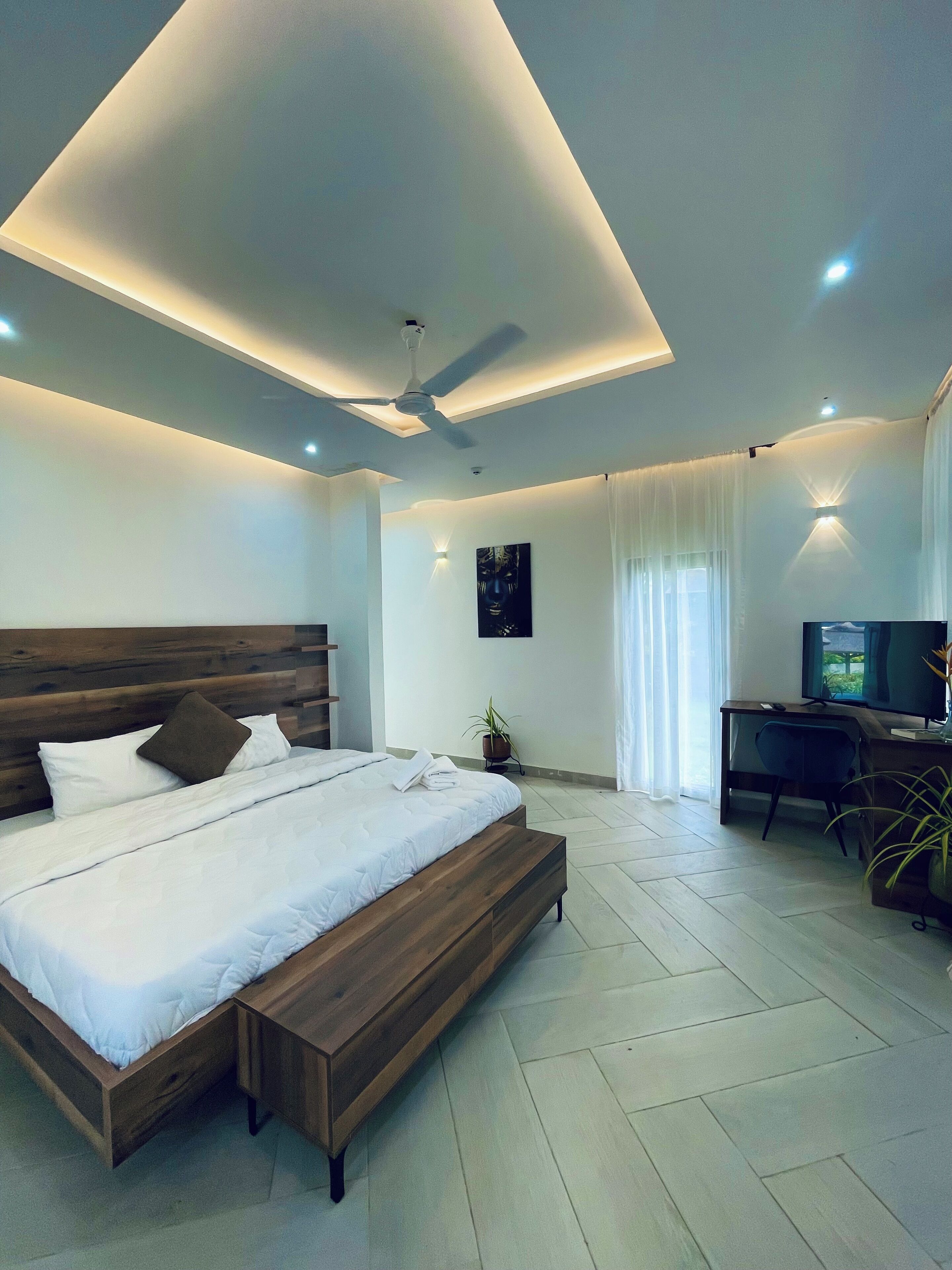 Une chambre à coucher moderne avec un lit en bois, un bureau et un téléviseur.