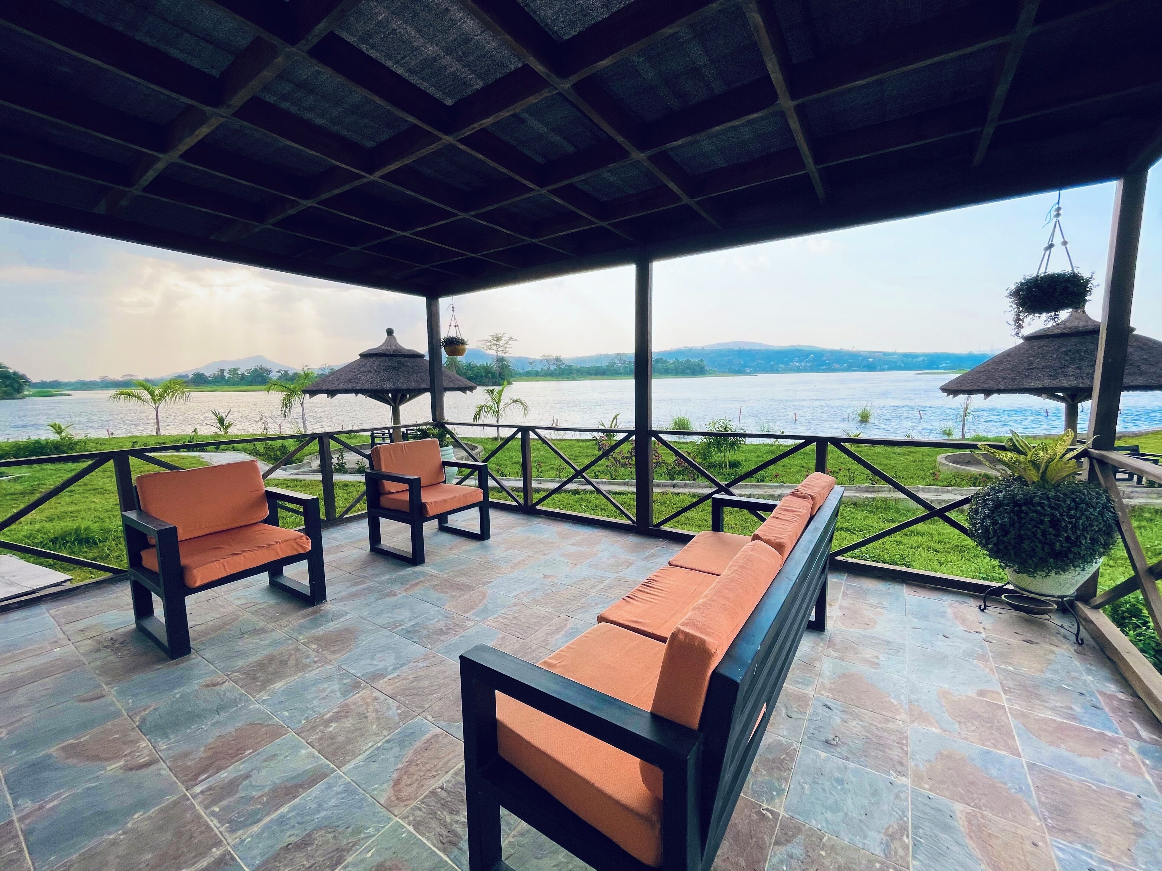 A covered outdoor seating area with a view of a lake and mountains.