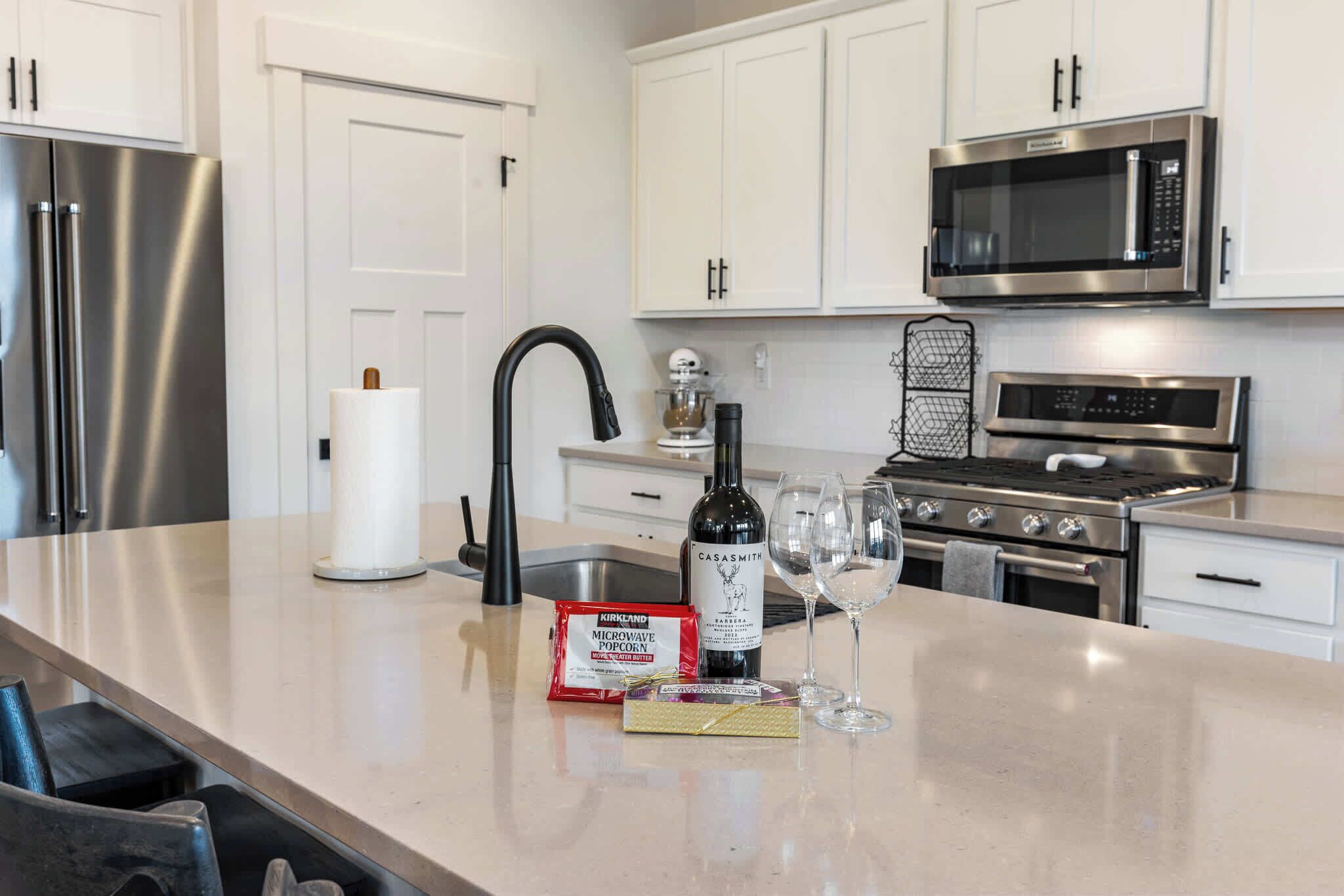 A modern kitchen with stainless steel appliances, a wine bottle, and a microwave.