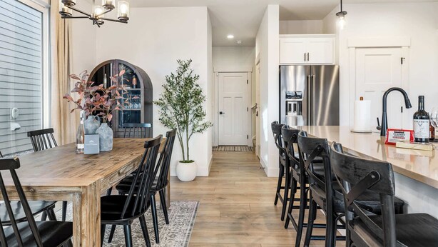 A modern kitchen with stainless steel appliances, a wooden dining table, and black chairs. - Antler's Peak | Bridger Views & Close to Airport (Belgrade)