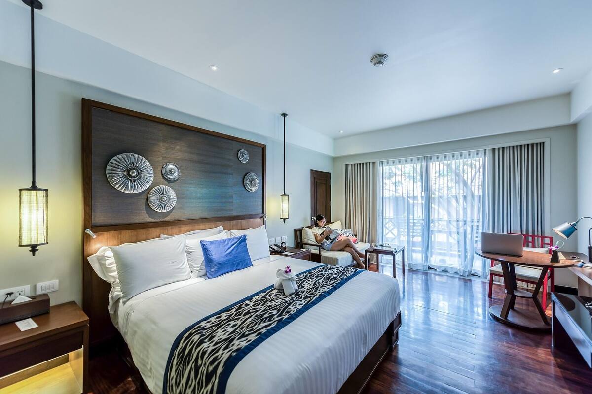 A hotel room with a large bed, a desk, and a chair. There are decorative plates on the wall above the bed.