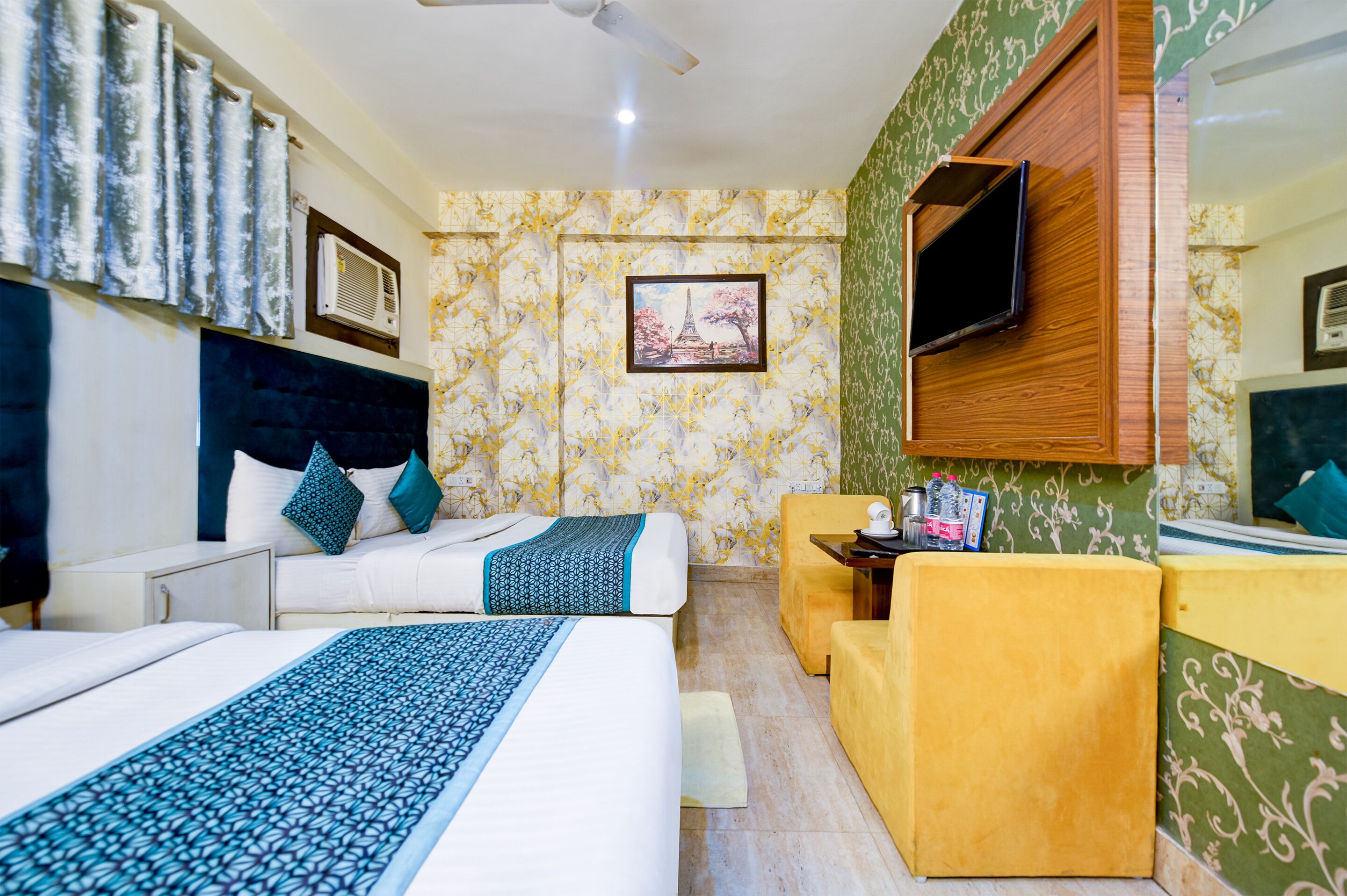Een hotelkamer met twee bedden, een televisie, een kleine tafel en een bank.