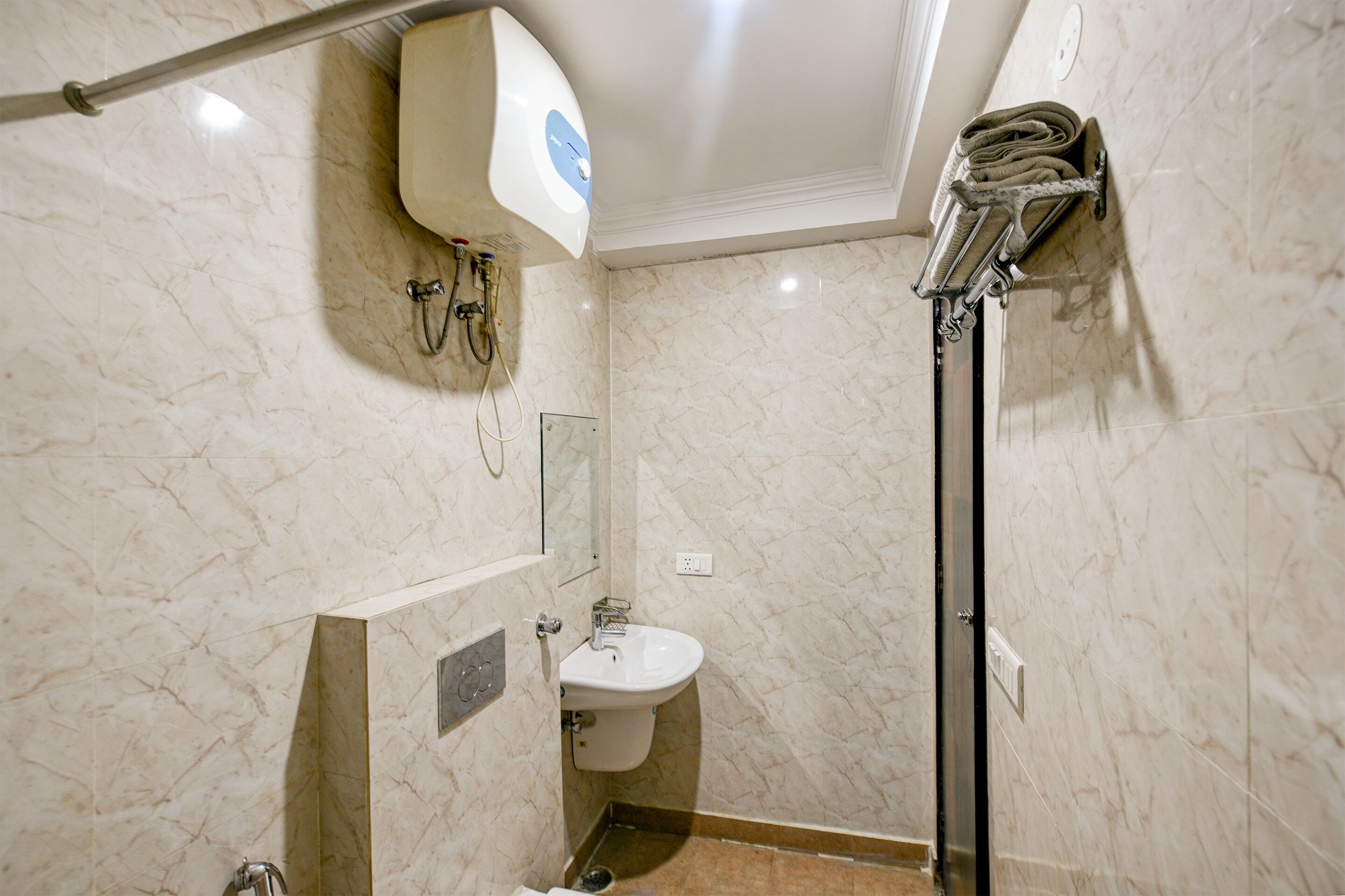 Une salle de bain avec un mur en marbre, un lavabo, un miroir et une douche.