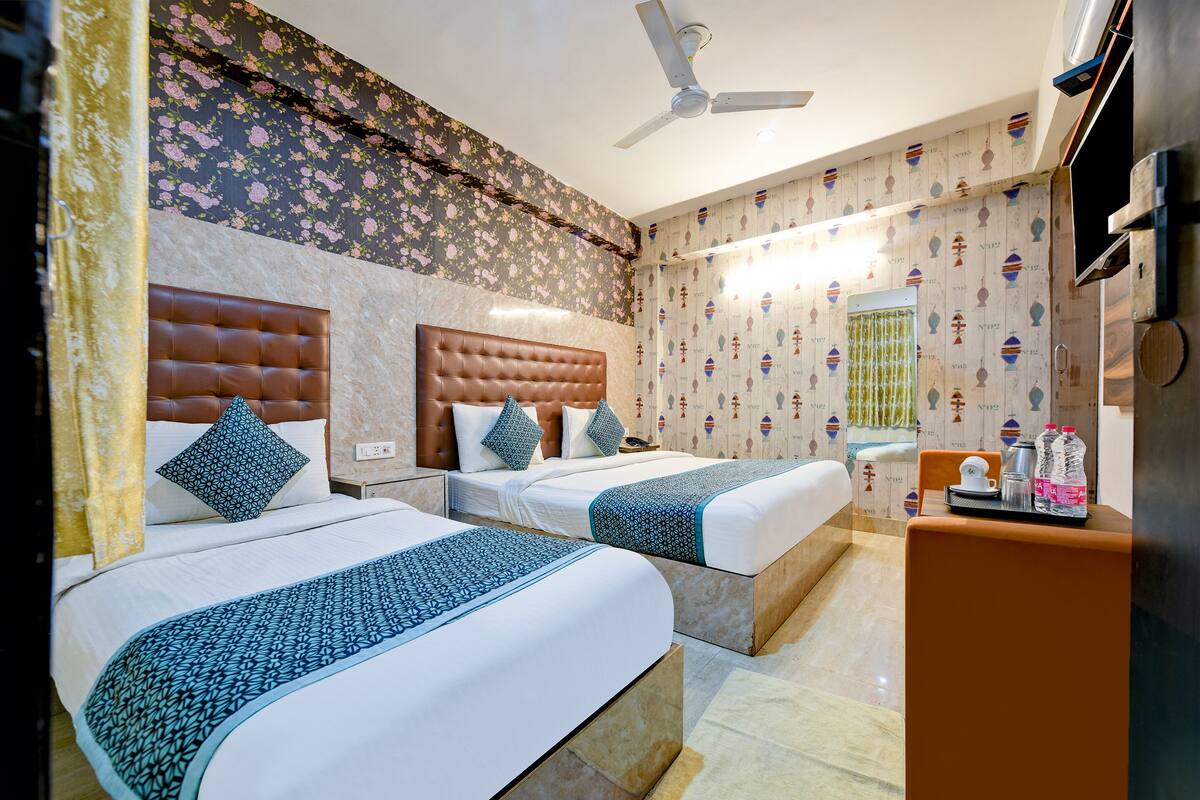 A hotel room with two beds, a ceiling fan, and a minibar.