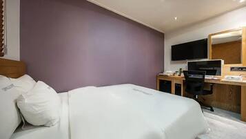 A hotel room with a bed, a desk with a computer, a television, and a mirror.