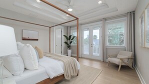 Une chambre à coucher avec un lit à baldaquin, une grande fenêtre avec des stores, une chaise et une plante en pot.