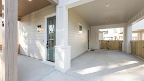 A covered patio area with a wooden deck, a white door, and a small window.