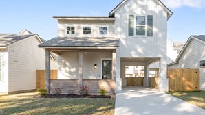 A two-story house with a front porch, a garage, and a wooden fence.
