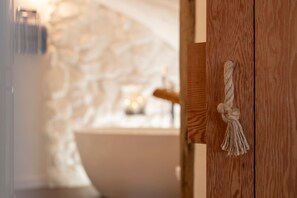 A wooden door with a rope handle, a stone wall, and a bathtub in the background. - Blue Horizon - Spectacular Coastal Views (Tenby)