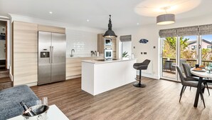 Et moderne køkken med en central ø, rustfrie stålapparater og et spiseområde med bord og stole.