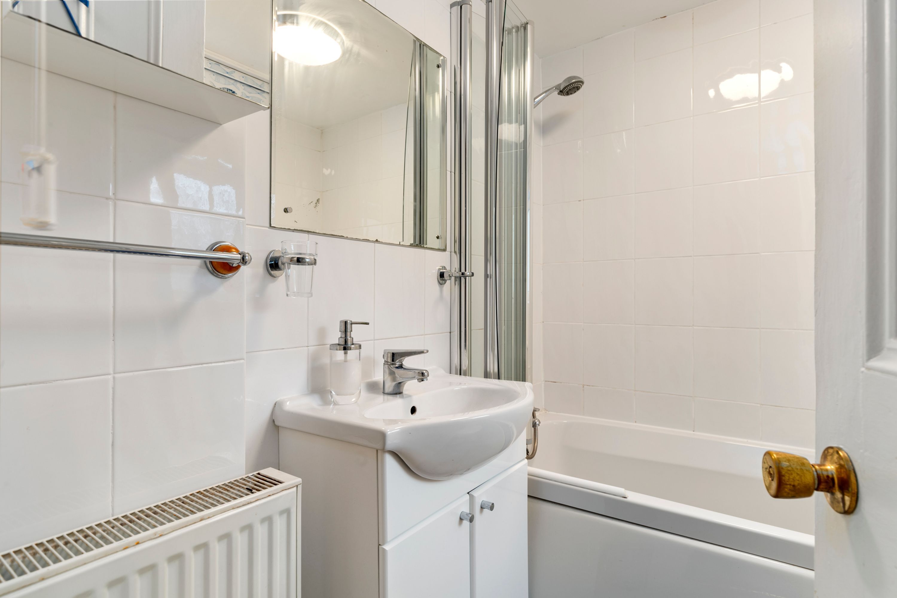 A bathroom with a white sink, mirror, and shower.