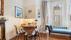 Een gezellige woonkamer met een eethoek, een blauwe bank en een open haard.