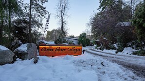 Eine verschneite Straße mit einem Holzschild, auf dem "Ohana Tekapo Collages" steht.
