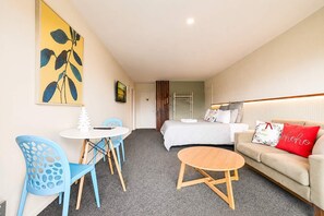Una habitación de hotel con cama, sofá, una mesita redonda y dos sillas.