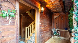 Ein Holzhäuschen im Inneren mit einer Holztreppe, einem Sessel und einer Laterne.