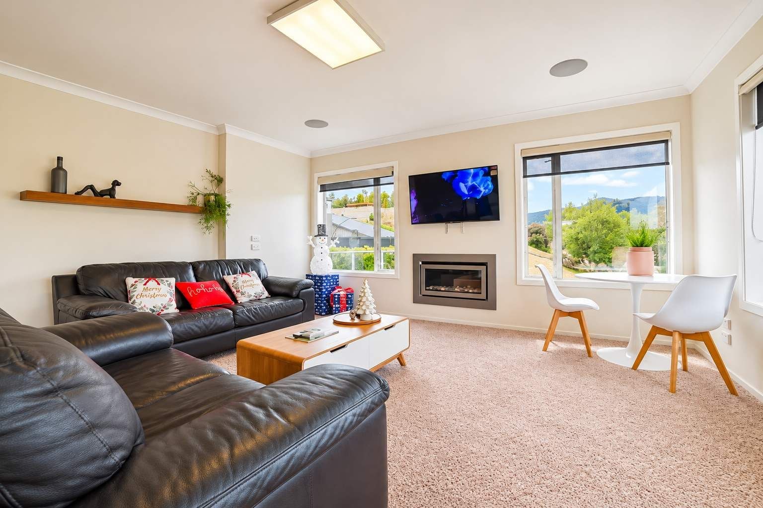 A living room with a fireplace, a sofa, a television, and a view of the outdoors.