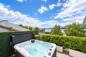 A hot tub on a balcony with a view of a residential area and mountains in the distance.