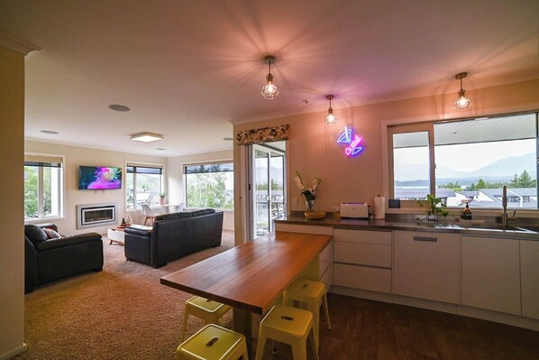 Una cocina moderna con una mesa de comedor de madera, taburetes de bar y un letrero de neón.