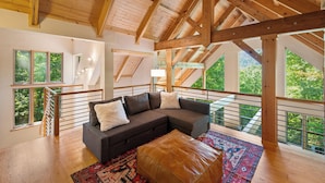 A spacious loft with a wooden ceiling, large windows, a gray sectional sofa, and a patterned rug. - Private Mountain Retreat near Breweries and Wineries (Lovingston)