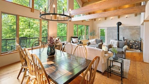 A spacious dining area with a wooden table and chairs, large windows offering a view of the outdoors, and a cozy seating area with a fireplace. - Private Mountain Retreat near Breweries and Wineries (Lovingston)