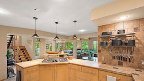A modern kitchen with wooden cabinets, a central island, pendant lighting, and a knife block on the wall. - Private Mountain Retreat near Breweries and Wineries (Lovingston)
