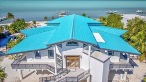 Une propriété située en bord de mer, avec un bâtiment au toit bleu, une porte en bois et un balcon.