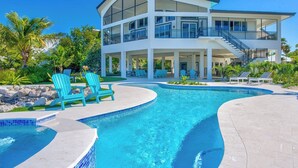 Une maison moderne à deux étages dotée d’une piscine, d’un espace salon extérieur et d’un patio couvert.