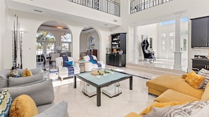 A spacious living area with a high ceiling, a dining area, and a kitchen.