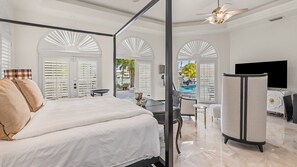 A bedroom with a bed, a desk, and a TV.