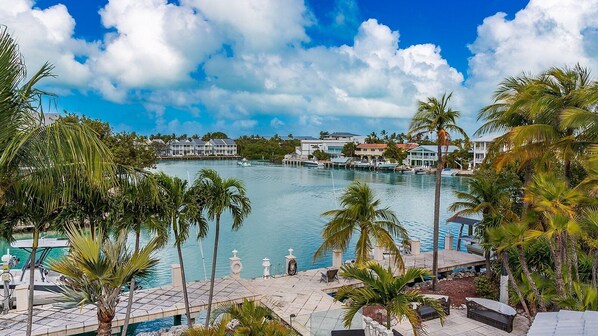 A waterfront hotel with a pool, palm trees, and a clear view of the water.