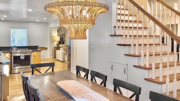 A modern kitchen with a dining area, wooden staircase, and pendant lighting. - 4 BR Beach House w/ Lush Backyard | Pet Friendly (Isle of Palms)