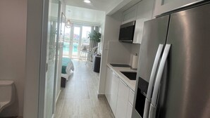 Een moderne keuken met een roestvrijstalen koelkast, witte kasten en een glazen deur naar een balkon.