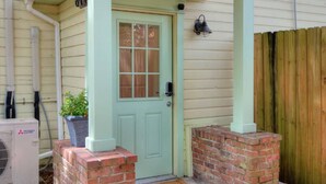 A house with a green door, brick steps, a doormat, and a wooden fence. - Charming Historic Studio Cottage (Lakeland)
