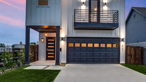 A modern two-story house with a garage, a balcony, and a well-lit entrance.